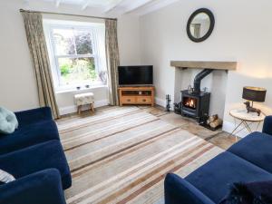 a living room with a blue couch and a fireplace at Chapel Cottage in Barnard Castle