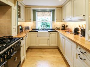 een keuken met witte kasten, een wastafel en een raam bij Chapel Cottage in Barnard Castle