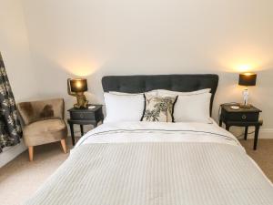 a bedroom with a white bed with two tables and a chair at Chapel Cottage in Barnard Castle