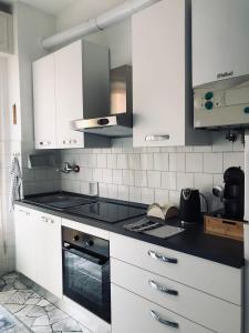 a kitchen with white cabinets and a stove top oven at Casa Emma 400 mt dal mare in Spotorno