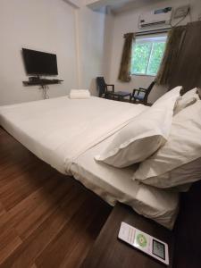 a large white bed in a room with a tv at Dia BNB in Assagao