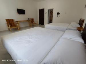 a room with two beds and a table and a television at ASM Roomstay-4-2 Queen Beds in Kuala Terengganu