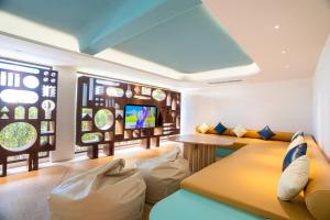 ein Wohnzimmer mit einem Sofa und einem TV in der Unterkunft Barcelo Coconut Island, Phuket in Phuket