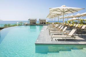 a swimming pool with lounge chairs and umbrellas at Anasa Luxury Resort in Elaiokhórion
