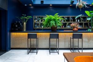 un bar bleu avec quatre tabourets et des plantes dans l'établissement 1K Paris, à Paris