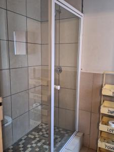a shower with a glass door in a bathroom at Warm, Comfy Duplex 5min Walk To North Park Mall in Pretoria