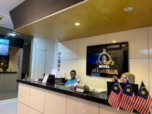 duas pessoas sentadas num balcão no átrio de um hotel em Al Amin Muslim Friendly Hotel em Kuala Lumpur