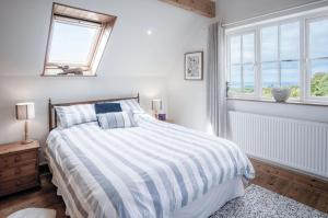 a white bedroom with a bed and two windows at Windy Walls - 3 Bedroom Holiday Home - Rhossili in Rhossili