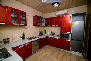La cuisine est équipée de placards rouges et d'un réfrigérateur en acier inoxydable. dans l'établissement Irofo City Apartments, à Accra