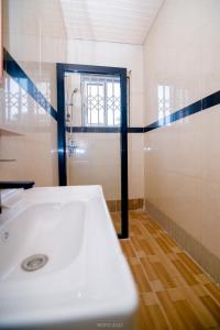 a bathroom with a shower and a white sink at Irofo City Apartments in Accra