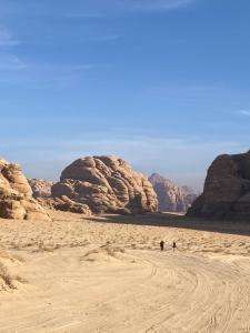 two people walking in the desert with mountains in the background at Wadi Rum fun camp in Wadi Rum