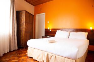 1 dormitorio con 1 cama blanca grande y pared de color naranja en Thayu Farm Hotel en Limuru