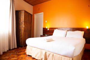 a bedroom with a large white bed with an orange wall at Thayu Farm Hotel in Limuru