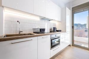 a kitchen with white cabinets and a sink and a window at Phaedrus Living: Luxury Penthouse Potamianou in Athens