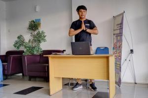 a man standing next to a desk with his hands crossed at OYO Life 92889 Apartement Grand Sentraland Karawang By A.t Room in Karawang
