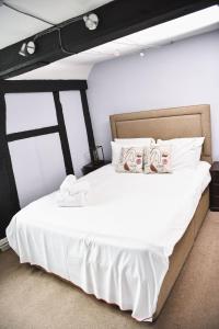 a bedroom with a large bed with white sheets at The Old Bell in Wooburn
