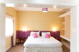 a bedroom with a large white bed with pink pillows at Thayu Farm Hotel in Limuru