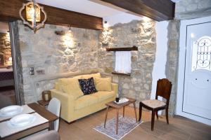 Elen's Suites Pramanta في برامانتا: غرفة معيشة مع أريكة صفراء وجدار حجري