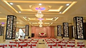 a banquet hall with red and white chairs and a chandelier at HOTEL SHIV PALACE in Jaipur