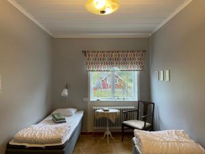 a room with two beds and a table and a window at Jokkmokks Vandrarhem Åsgård in Jokkmokk