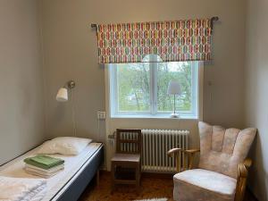 um quarto com uma cama, uma cadeira e uma janela em Jokkmokks Vandrarhem Åsgård em Jokkmokk