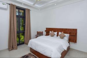 a bedroom with a bed and a large window at JOY B Apartment 2 in Kiembi Samaki