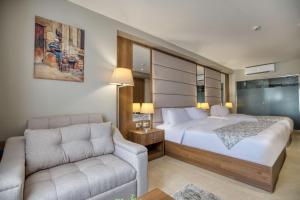 een slaapkamer met een bed, een stoel en een bank bij NOZOL PYRAMIDS HOTEL in Caïro
