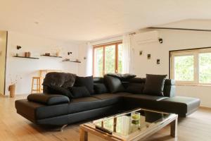 een woonkamer met een zwarte bank en een tafel bij Chalet en pleine nature Pomerol in Pomerol