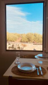 una mesa con platos y gafas y vistas a una ventana en Andromeda en Tsoútsouros