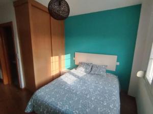 a bedroom with a bed with a blue wall at Ático DeCasBri in Talavera de la Reina