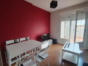 a room with a white table and chairs and a red wall at Ático DeCasBri in Talavera de la Reina