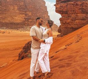 a man and a woman standing in the desert at Wadi Rum Red Sand Camp in Wadi Rum