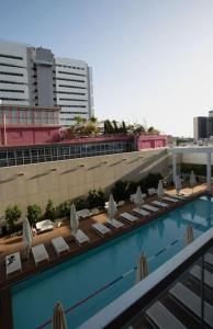 uma vista para uma piscina com cadeiras e um edifício em Meier on Rothschild 36 em Tel Aviv