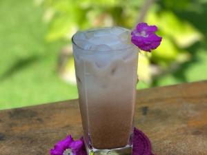 a drink sitting on a table with purple flowers at Bloom Garden Bed & Breakfast in Siem Reap