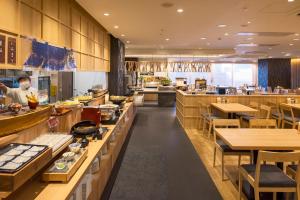 函館市にあるホテルグローバルビュー函館の多くのテーブルを持つレストランで、シェフが料理を作っています。