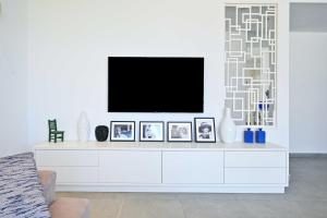 a white living room with a tv on a white wall at Granite 2BR by HolyGuest in Tel Aviv