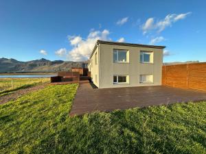 a house on a field with a wooden deck at Vatnsholt in Snæfellsnes - Birta Rentals in Snæfellsbær