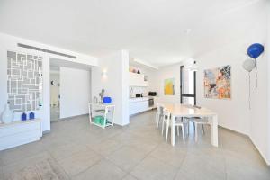 een keuken en eetkamer met witte muren en een tafel en stoelen bij Granite 2BR by HolyGuest in Tel Aviv