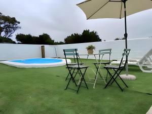 een patio met een tafel en stoelen en een parasol bij Bungalow para familias y parejas in Conil de la Frontera