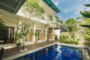 une villa avec une piscine et une maison dans l'établissement Happy Devi Guesthouse, à Canggu