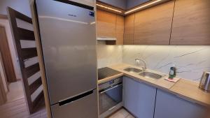 a kitchen with a stainless steel refrigerator and a sink at Queen Apartament Centrum z garażem in Mińsk Mazowiecki