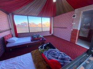 a room with two beds and a window in a tent at Wadi Rum fun camp in Wadi Rum