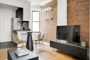 a living room with a large television and a brick wall at Kips Bay 1BR w WD nr E River 6 Train NYC-829 in New York