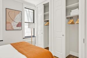 a bedroom with white walls and a bed with an orange blanket at Kips Bay 1BR w WD nr E River 6 Train NYC-829 in New York