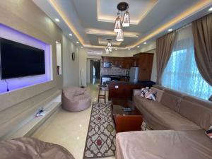 Sharm Hills Aqua park Resort في شرم الشيخ: غرفة معيشة مع أريكة وتلفزيون بشاشة مسطحة