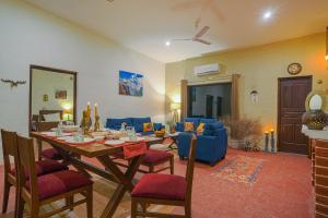 a living room with a table and blue chairs at SaffronStays The Lodge at Dalewal, Hoshiarpur in Hoshiārpur