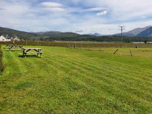 two picnic tables in a field with mountains in the background at Clovullin Croftview Pod in Ardgour