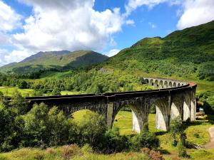a train on a bridge with mountains in the background at Clovullin Croftview Pod in Ardgour