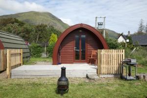 a small wooden cabin with a wooden deck at Clovullin Croftview Pod in Ardgour
