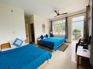 1 dormitorio con 2 camas y ventana grande en Rahgir Mcleodganj en McLeod Ganj